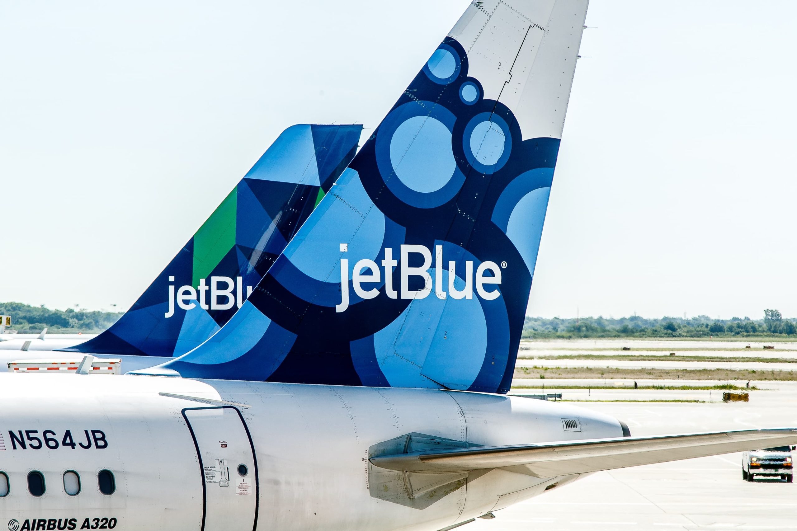 Dos aviones de JetBlue están estacionados junto a las puertas esperando el embarque de pasajeros.