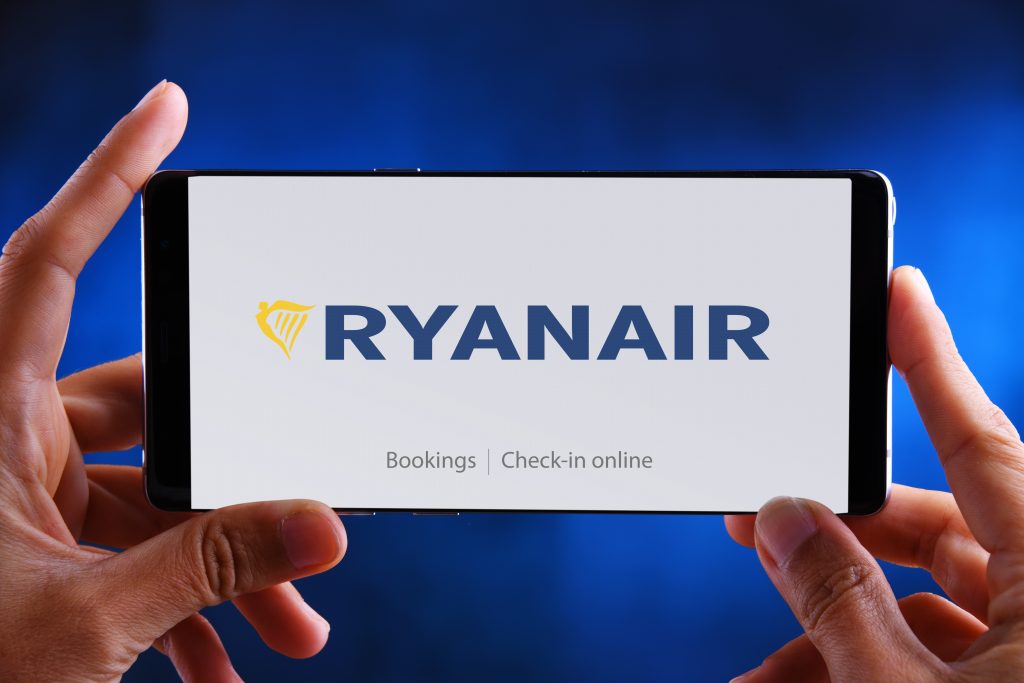Manos sosteniendo un smartphone mostrando el logotipo de Ryanair